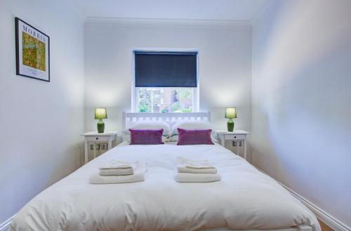 una camera da letto con un grande letto bianco con cuscini viola di Modern 2 Bedroom Apartment a Romford
