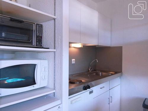 une cuisine avec un micro-ondes et un évier dans l'établissement Studio cosy pour 4 pers. à 90m des pistes – Balcon sud, commerces et école de ski à proximité - FR-1-405-65, à L'Alpe-d'Huez