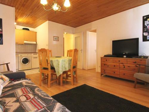 un salon avec une table avec des chaises et une télévision dans l'établissement Appartement cosy à L'Alpe d'Huez, 5 pers, balcon, proche pistes et centre, animaux acceptés - FR-1-405-9, à L'Alpe-d'Huez