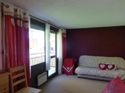 Cette chambre comprend un lit et une fenêtre avec un canapé. dans l'établissement Studio 4 pers, coeur station, prox pistes, balcon, animaux OK, TV, cuisine équipée, casier à skis - FR-1-405-41, à L'Alpe-d'Huez