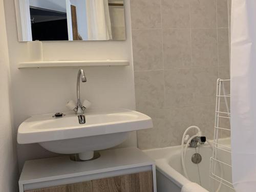 une salle de bain avec un lavabo, un miroir et une baignoire dans l'établissement Appartement cosy 4 pers. avec balcon sud, proche commerces et remontées, L'Alpe d'Huez - FR-1-405-61, à L'Alpe-d'Huez