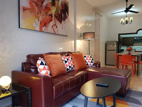 a living room with a brown leather couch and a table at Naka Tangerine Holiday Home by Bcare in Ban Rangeng