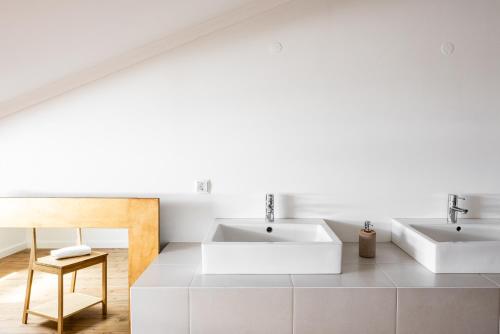a white bathroom with two sinks and a chair at Courela da Lameira in Reguengos de Monsaraz