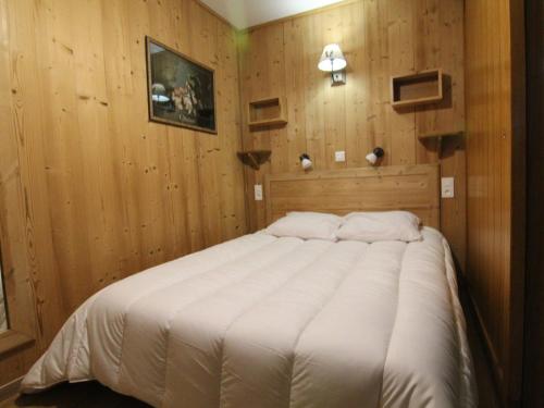 un grand lit dans une chambre aux murs en bois dans l'établissement Appartement 2P avec Balcon Sud et Proche Pistes – L’Alpe d’Huez - FR-1-405-38, à L'Alpe-d'Huez