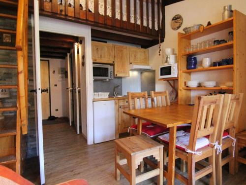 une cuisine avec une table en bois et un réfrigérateur blanc dans l'établissement Charmant 2 pièces avec mezzanine, balcon, et accès direct aux pistes - Vieil Alpe - FR-1-405-80, à L'Alpe-d'Huez