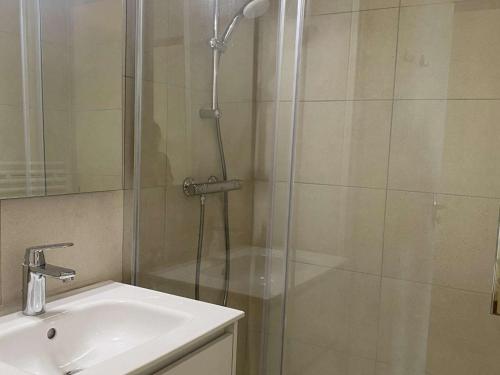 une douche avec une porte vitrée à côté d'un lavabo dans l'établissement Appartement 4 pers, balcon sud, quartier Passeaux - Alpe d'Huez - FR-1-405-111, à L'Alpe-d'Huez