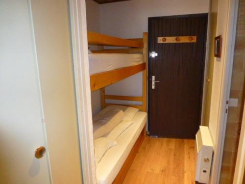 Cette petite chambre comprend 2 lits superposés et une porte. dans l'établissement Studio cosy pour 4 à L'Alpe d'Huez, proche pistes et commerces, balcon sud, casier à skis. - FR-1-405-117, à L'Alpe-d'Huez