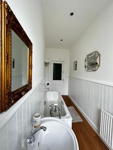 a white bathroom with a sink and a mirror at THE LAZY LION - Spacious 2 Bedroom - Town Centre Holiday Home Apartment in Port Glasgow