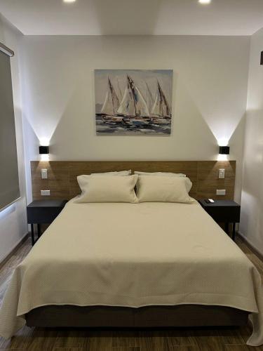 - une chambre avec un grand lit blanc et 2 tables de chevet dans l'établissement Kiran Lodging Guayaquil, à Guayaquil