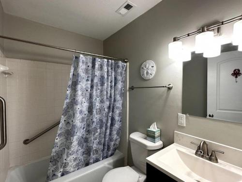 a bathroom with a shower curtain and a toilet and a sink at Nautical Nirvana-Waterfront Joys from Sunrise Paddles to Hot Tub Sunsets in Panama City
