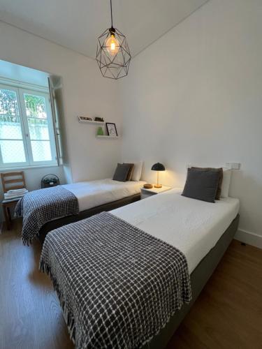 a bedroom with two beds and a pendant light at Mouraria Best Apto in Lisbon