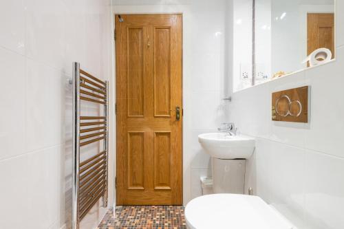 a bathroom with a toilet and a wooden door at 138 North Street - luxury 2 bed 2 bath with secret garden, summerhouse, putting green in St. Andrews
