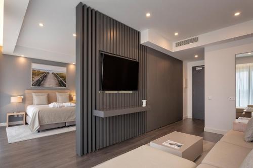 a bedroom with a bed and a tv on a wall at Longevity Health & Wellness Hotel - Adults Only in Alvor