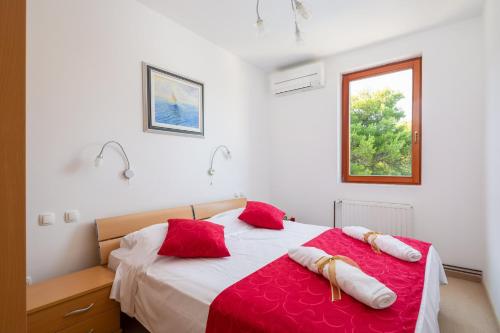 a bedroom with two beds with red pillows and a window at Luxury Villa Bella Vista with Swimming Pool in Betina
