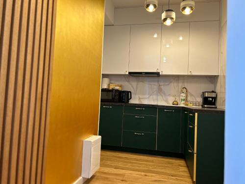 a kitchen with green cabinets and a yellow wall at Brand New !!! Baltic Marina Residence Sauna & Fitness Apartments- Royal Green Apartments, Ferienwohnung polnische Ostsee in Kołobrzeg