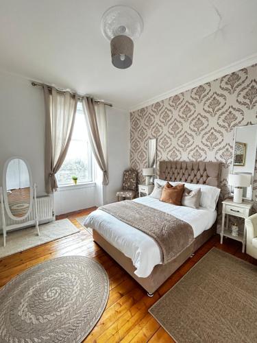 ein Schlafzimmer mit großem Bett und Fenster in der Unterkunft THE LAZY LION - Spacious 2 Bedroom - Town Centre Holiday Home Apartment in Port Glasgow