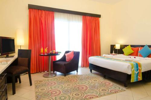 a bedroom with a bed and a desk and a window at Swiss Inn Teda Hotel & Aqua Park in Ain Sokhna