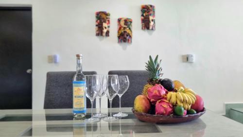 a glass table with a bowl of fruit and wine glasses at On The Beach - Seaside Sunrise Haven 3 Bedrooms SEA VIEW in Cancún
