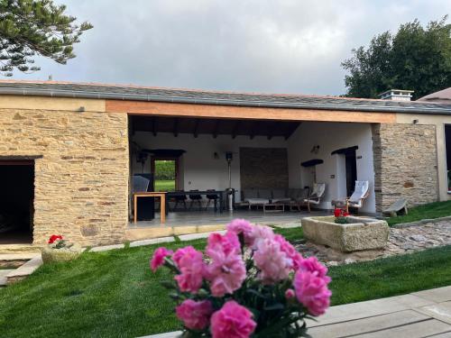 a stone house with pink flowers in the yard at Araucaria House in Barreiros