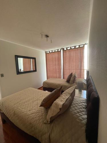 een hotelkamer met 2 bedden en een bank bij Departamento Antofagasta-Icono in Antofagasta