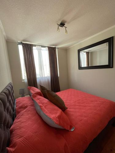 een slaapkamer met een bed met rode lakens en kussens bij Departamento Antofagasta-Icono in Antofagasta