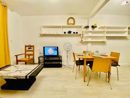ein Wohnzimmer mit einem Tisch, Stühlen und einem TV in der Unterkunft Two Bedroom house on Ground Floor in London in London