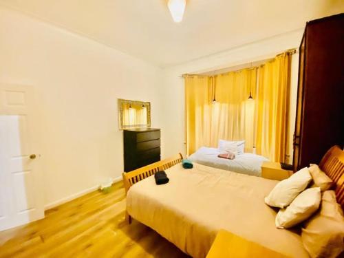 1 Schlafzimmer mit 2 Betten und einem Fenster mit gelben Vorhängen in der Unterkunft Two Bedroom house on Ground Floor in London in London