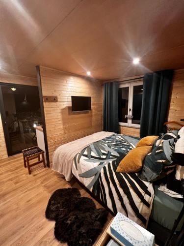 Chalet Ecolodge Mazion في Mazion: غرفة نوم فيها سرير وتلفزيون
