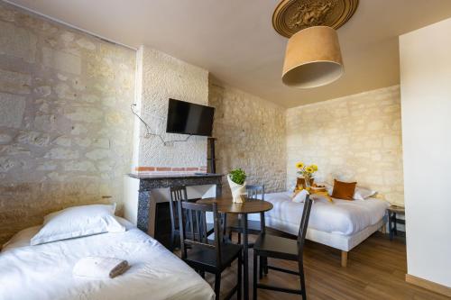 Cette chambre comprend deux lits et une table avec une cheminée. dans l'établissement L'Authentic, à Saint-Aignan