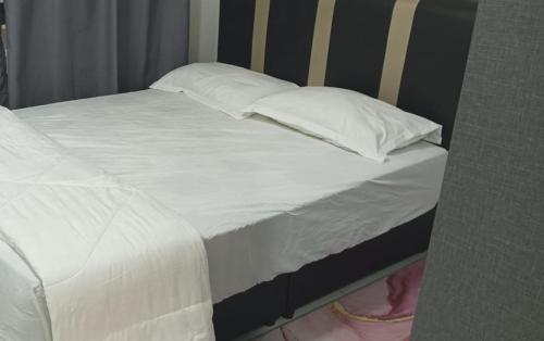 Una cama con sábanas blancas y almohadas. en D CAMYLIA PUTRAJAYA HOMESTAY, en Putrajaya