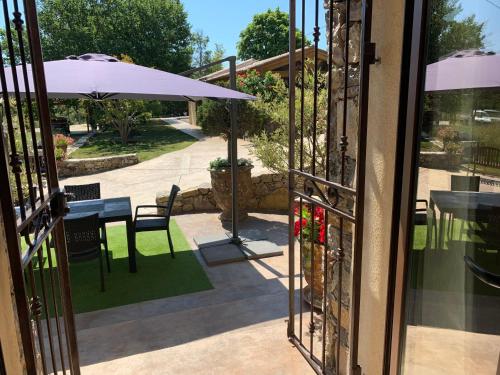 an open door to a patio with a table and an umbrella at Le Hameau des vanades in Ampus