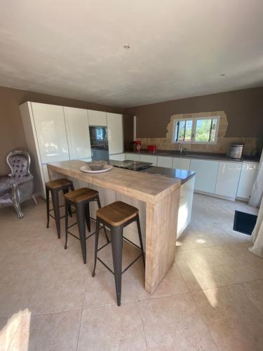 a kitchen with a large wooden table and stools at Le Hameau des vanades in Ampus
