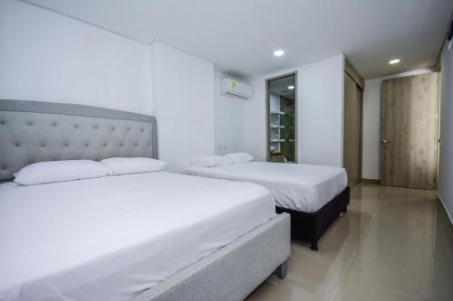 2 camas en una habitación de hotel con sábanas blancas en APARTAMENTO OCEAN DRIVE 410 CARTAGENA en Cartagena de Indias