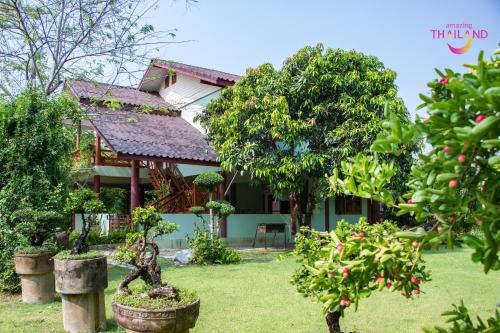 una casa con un jardín delante de ella en บ้านห้วยลูกนกฟาร์มสเตย์ Banhuailuknok Farmstay en Ratchaburi