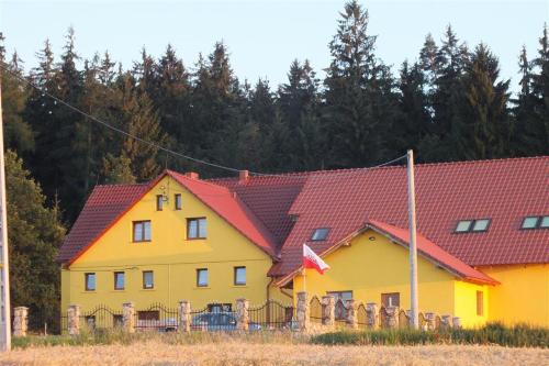 ein großes gelbes Haus mit roten Dächern in der Unterkunft Dom Na Leśnej Górze in Leśna