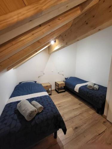 deux lits dans une chambre avec plafonds en bois dans l'établissement Maison au coeur des montagnes de l'Oisans, à Le Bourg d'oisans