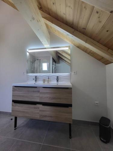 une salle de bain avec un lavabo et un grand miroir dans l'établissement Maison au coeur des montagnes de l'Oisans, à Le Bourg d'oisans