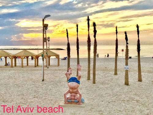 a statue of a person on a beach with palm trees at C.B.O. Tel Aviv 117 Allenby St. in Tel Aviv