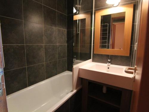 W łazience znajduje się umywalka, wanna i lustro. w obiekcie Appartement Huez, 1 pièce, 4 personnes - FR-1-405-152 w LʼAlpe-dʼHuez