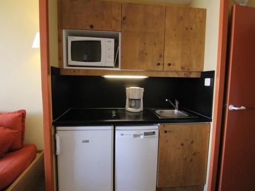 une petite cuisine avec un évier et un micro-ondes dans l'établissement Studio cosy 4 pers à l'Alpe d'Huez – Balcon sud, proche pistes et commerces, animaux acceptés - FR-1-405-152, à L'Alpe-d'Huez