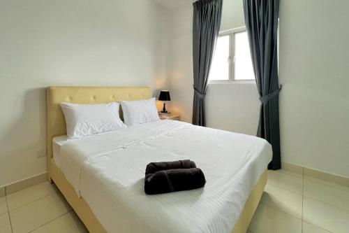 un grande letto bianco con un asciugamano nero sopra di Alanis Suites By Semathomes a Sepang