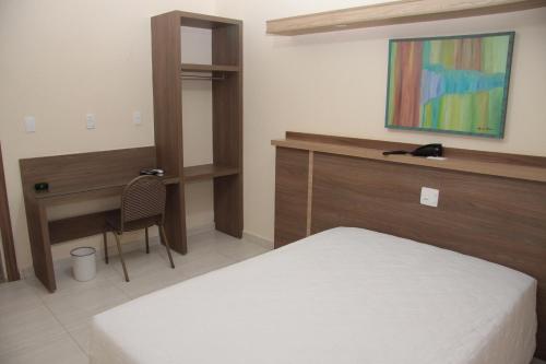 a bedroom with a bed and a desk and a table at Prince Hotel in Ribeirão Preto