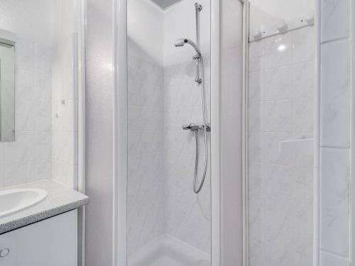 ein weißes Bad mit einer Dusche und einem Waschbecken in der Unterkunft Studio Luz-Saint-Sauveur, 1 pièce, 4 personnes - FR-1-402-59 in Luz-Saint-Sauveur