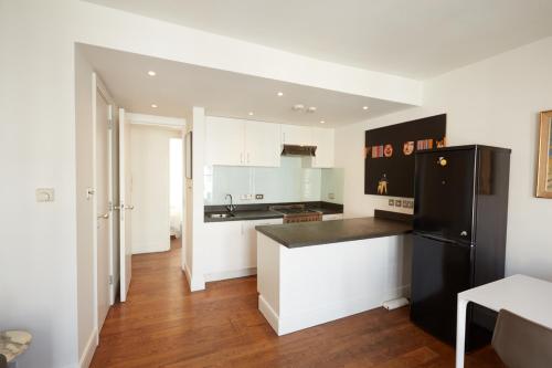a kitchen with white cabinets and a black refrigerator at Notting Hill, Portobello, Kensington Chelsea in London