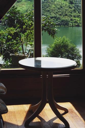 a table in front of a window with a view at Nhà Bao La - Hồ Đak Long Thượng in Bao Loc