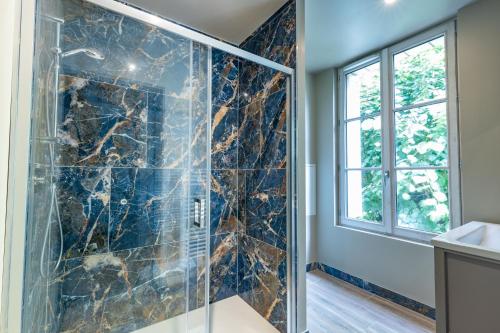 La salle de bains est pourvue d'une cabine de douche en verre et d'une fenêtre. dans l'établissement L'Agate Bleue, à Saint-Aignan