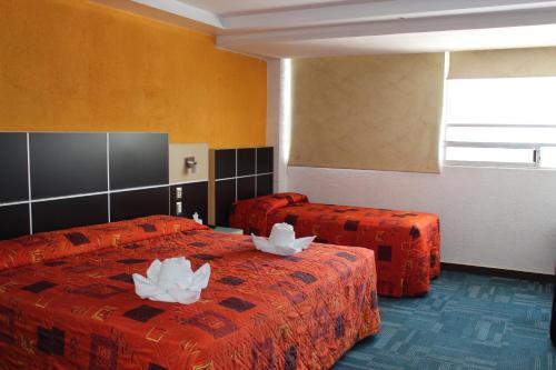 Habitación de hotel con 2 camas con flores blancas. en Hotel Aqueronte, en Ixtapaluca