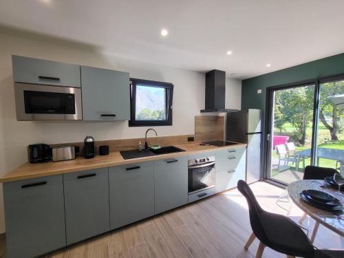 une cuisine avec des armoires blanches et une table et une salle à manger dans l'établissement Maison au coeur des montagnes de l'Oisans, à Le Bourg d'oisans