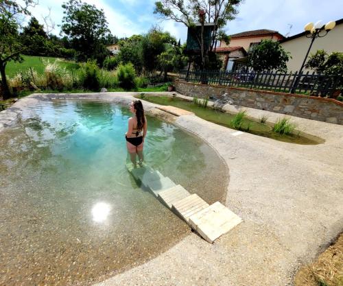 una mujer parada en el agua en una piscina en Il Casale di Lucullo, en Lucignano