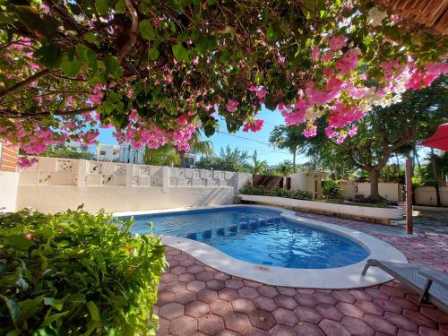 a swimming pool in a yard with pink flowers at Cabañas Puerto Morelos in Puerto Morelos